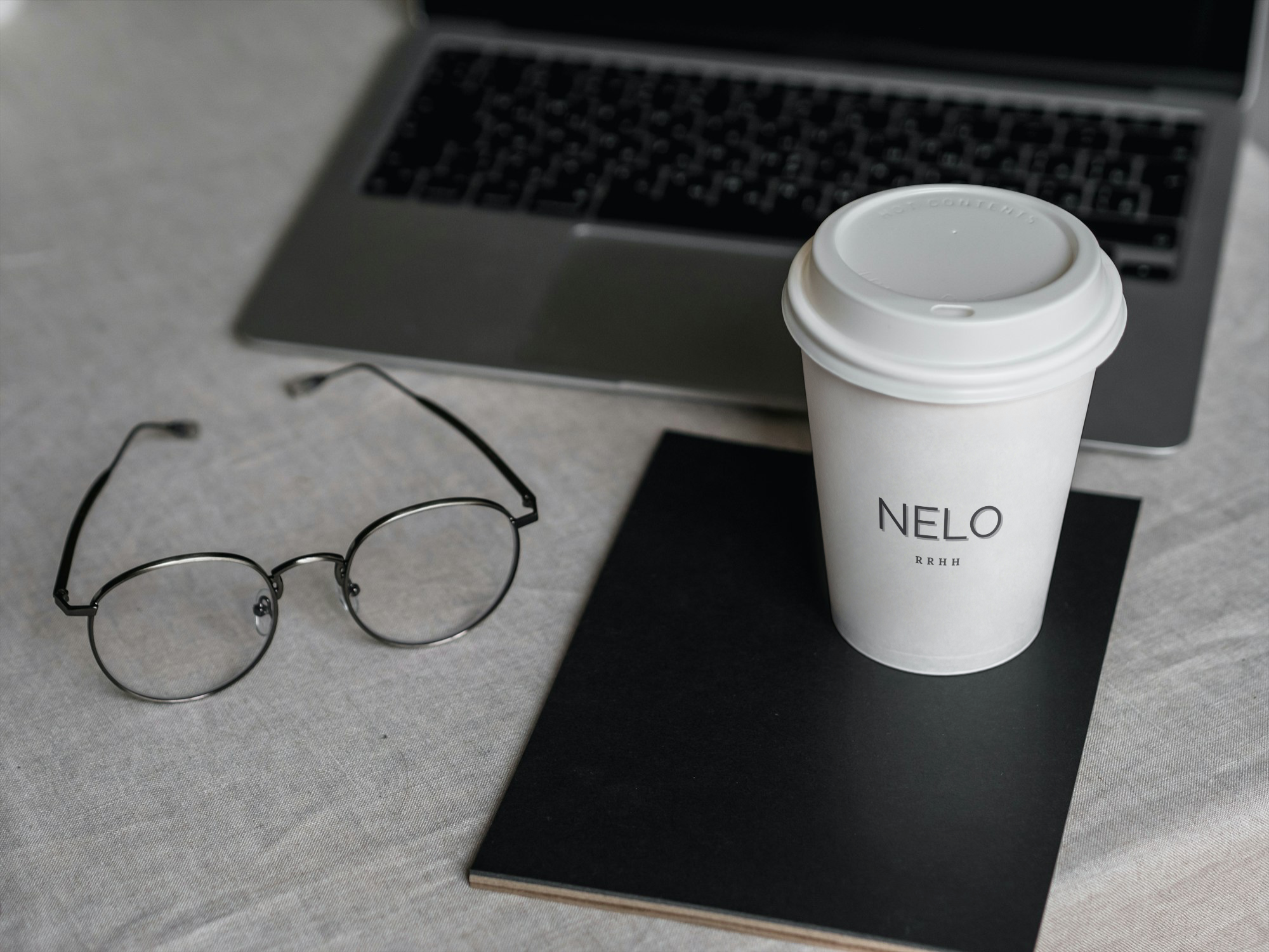 Professional workspace with laptop, glasses and coffee